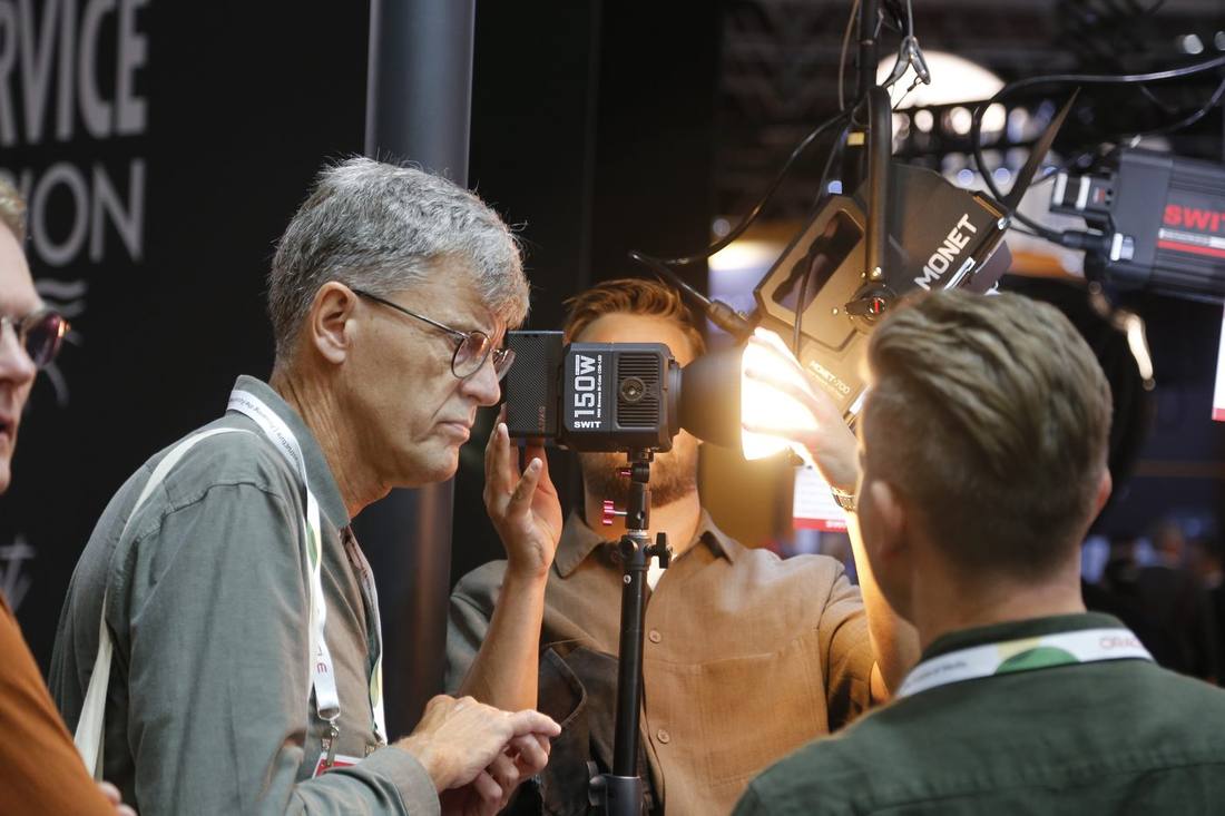 Visitors testing the SWIT Mini-150B 150W bi-color COB light at the IBC2026 booth