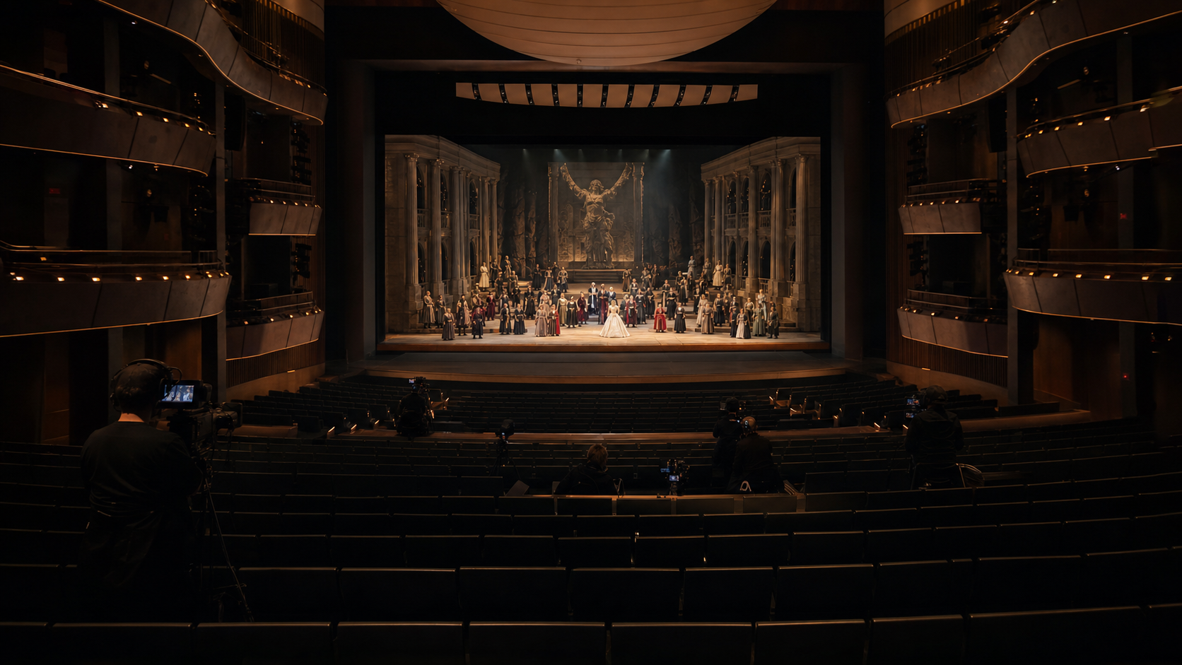 Opera performance being recorded in a theatre with dark audience seating and multiple camera positions